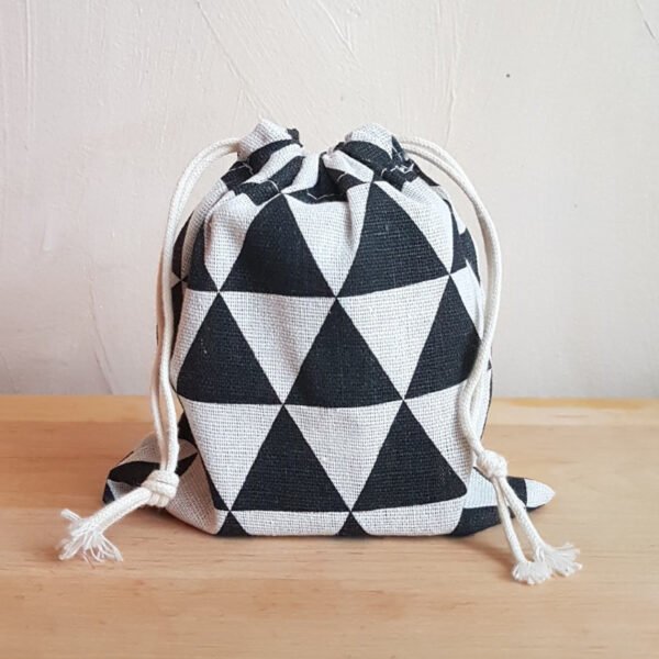 Väike must-valgete kolmnurkadega riidest kott pealt suletava nööriga